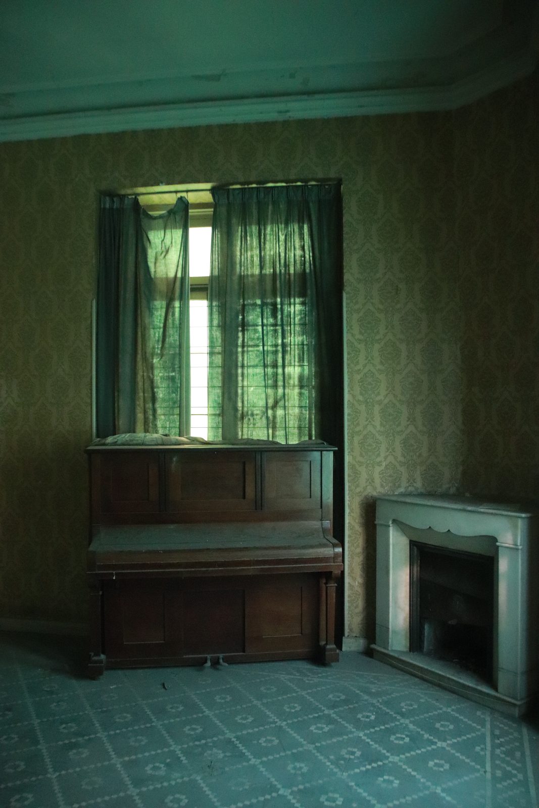 Piano abandonado junto a la chimenea, frente a una ventana